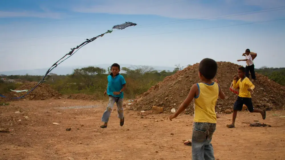 Des enfants courent et jouent en plein air en faisant voler un cerf-volant