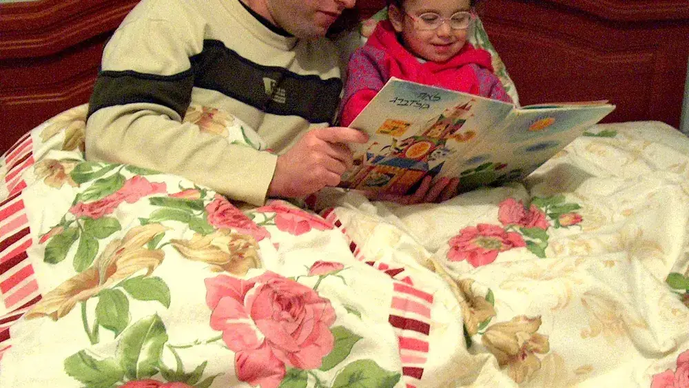 Un père lisant une histoire du soir à sa fille dans son lit