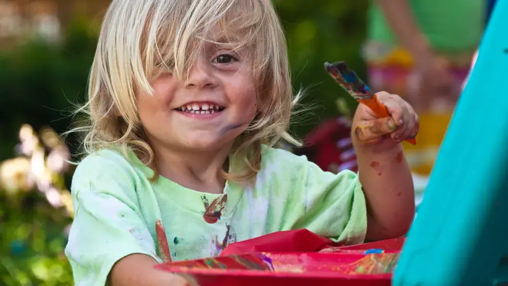 Enfants peignant et dessinant sur une table dans une pièce lumineuse