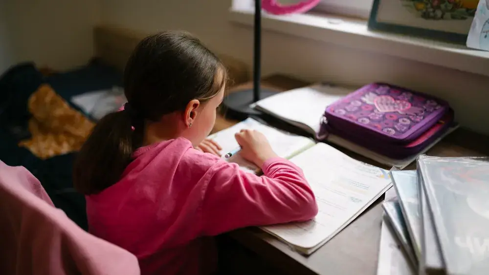 Une enfant fait ses devoirs à son bureau dans sa chambre