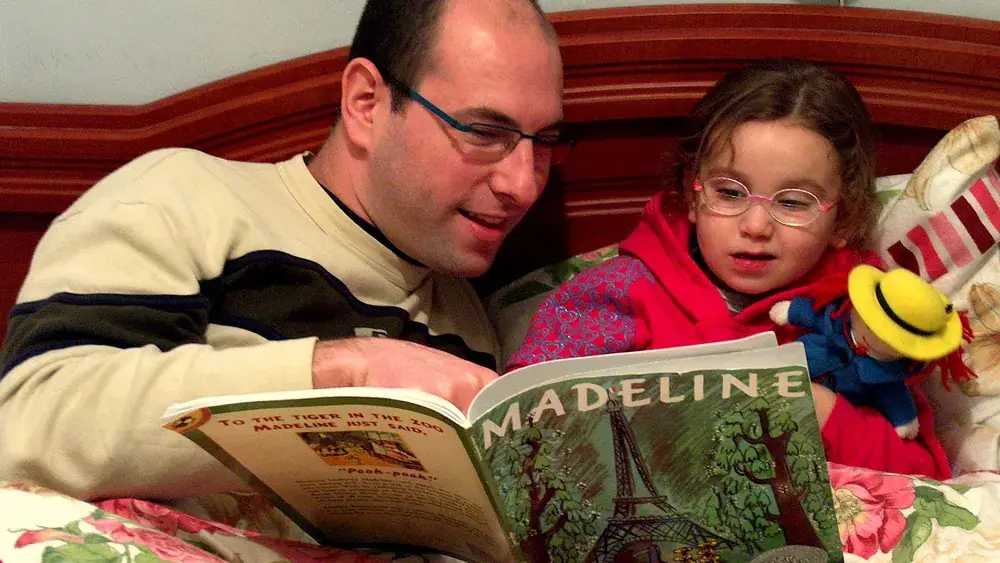 Un père lit une histoire du soir à sa fille dans son lit